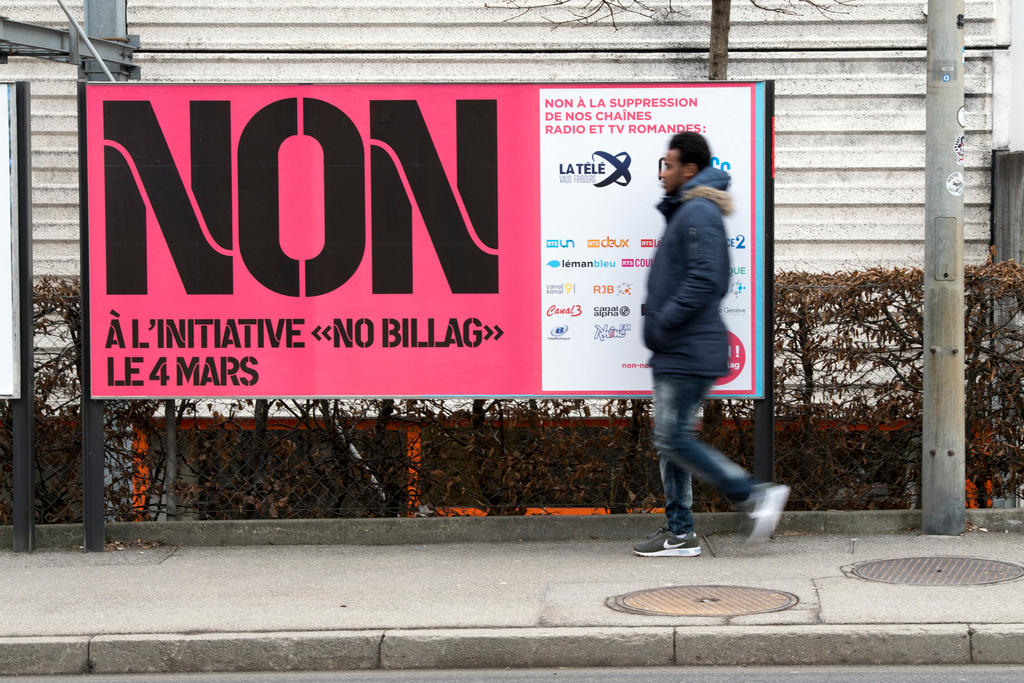 A person passes in front of a billboard with an ad campaigning against the NoBillag initiative