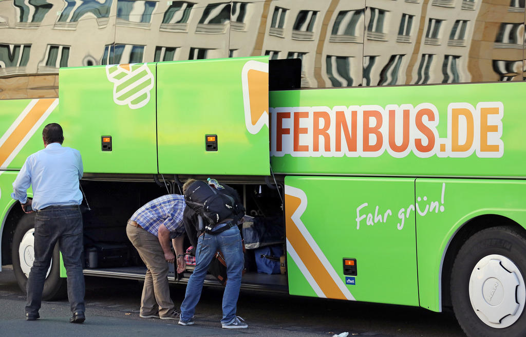 people putting luggage in side of long distance coach