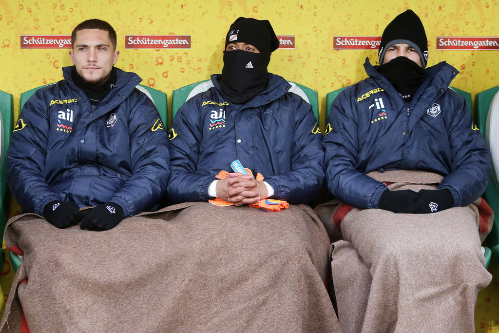 Jugadores suplentes del FC Lugano en la banca, tapados con mantas