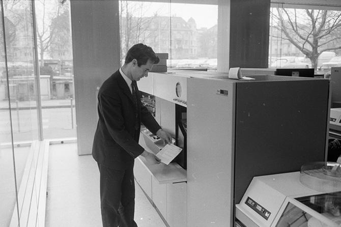 A man takes paper from a computer.