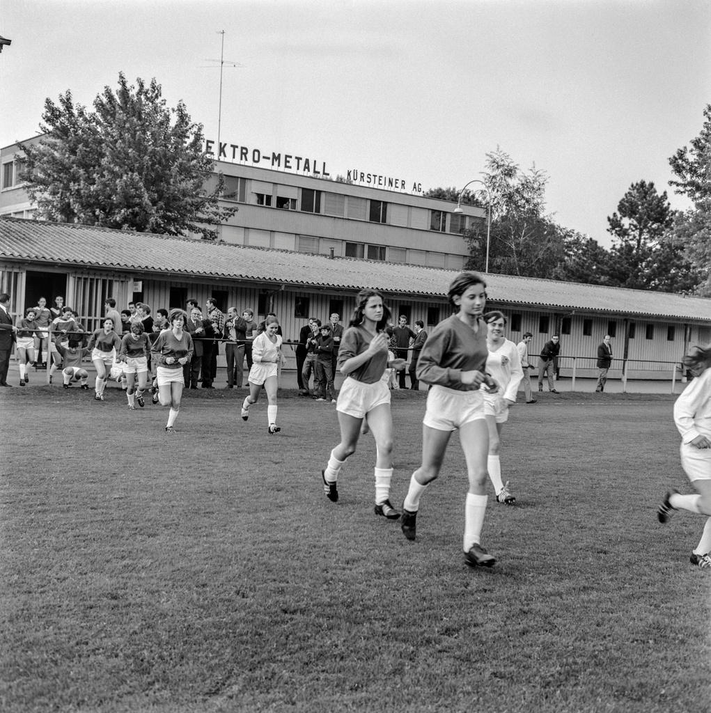 Links: Die Fussballerinnen des FCZ, rechts: FC Heuried, laufen vor dem Spiel auf einem Sportplatz.