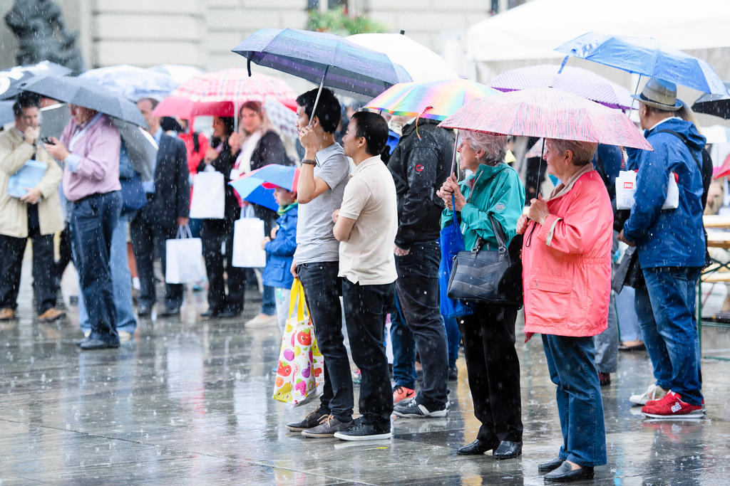 Auscland-Schweizerinnen und -Schweizer unter Regenschirmen.