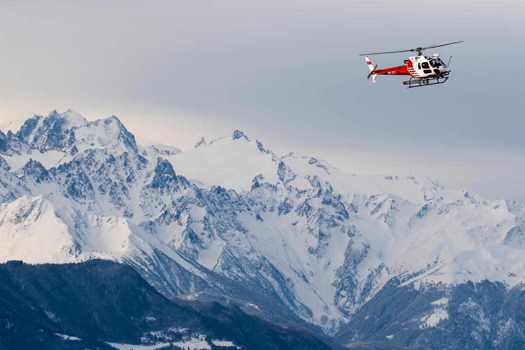 A helicopter surveys the site where an avalanche was artificially triggered for test purposes in Valais, Switzerland