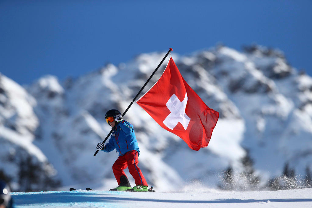 A young Swiss skier holding a Swiss flag