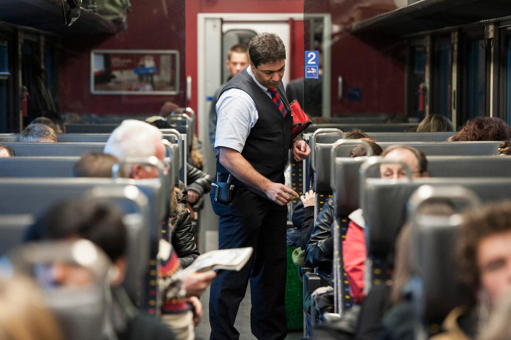 An inspector checks commuters tickets on a train from Lausanne to Brig