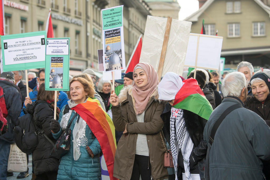 People march with posters and Palestinian flags in Bern