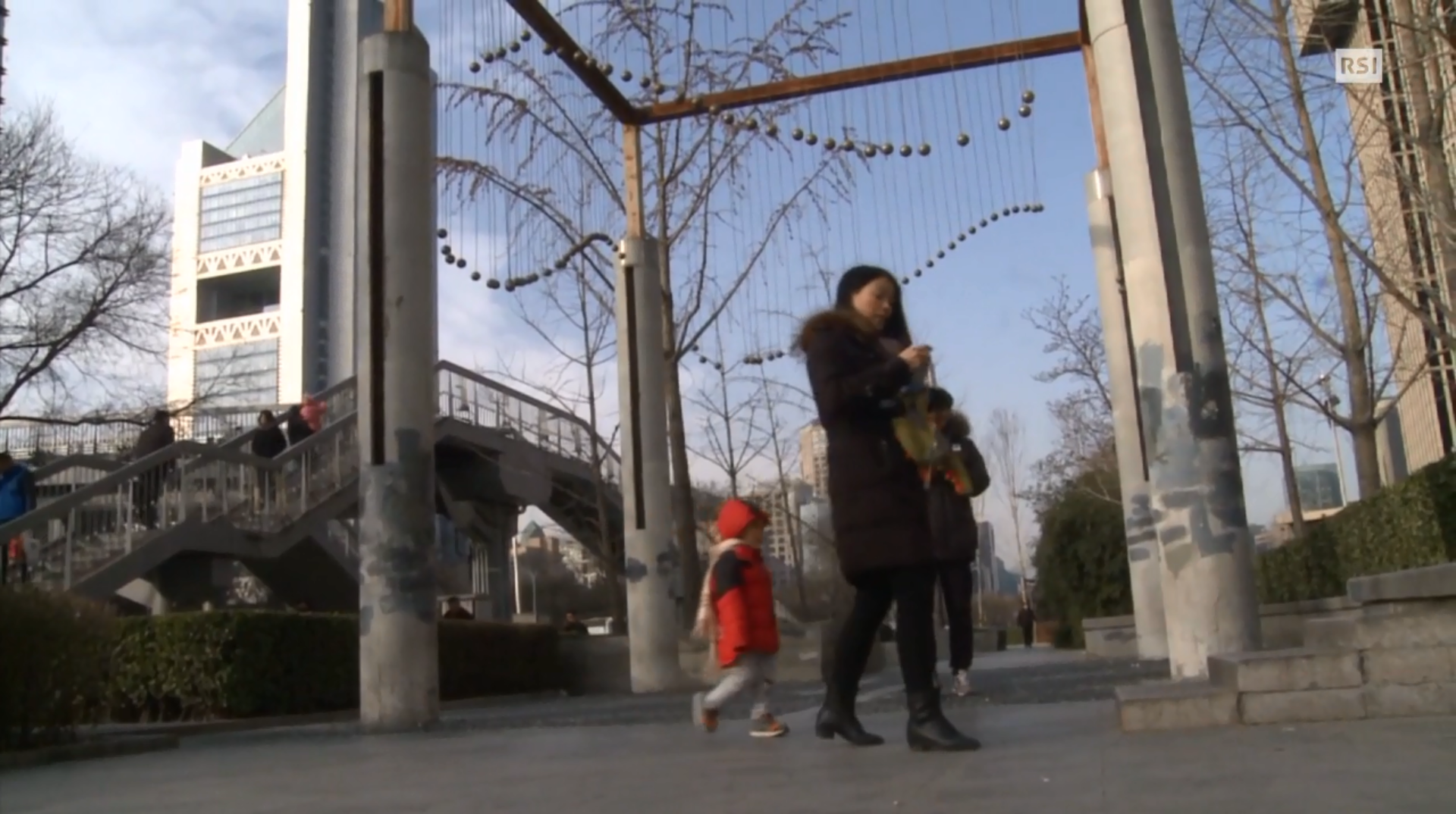 Immagine di una mamma con bambino che passeggia per Pechino in un giorno di bel tempo