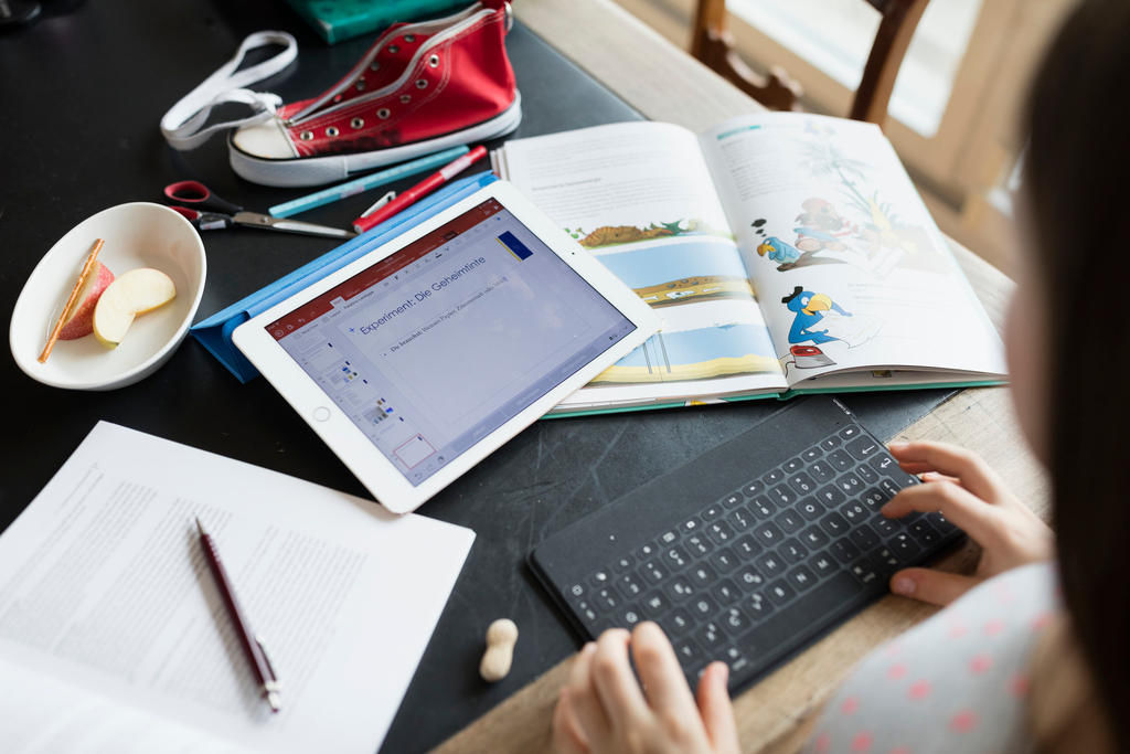 A ten year old girl does her homework on a tablet pc