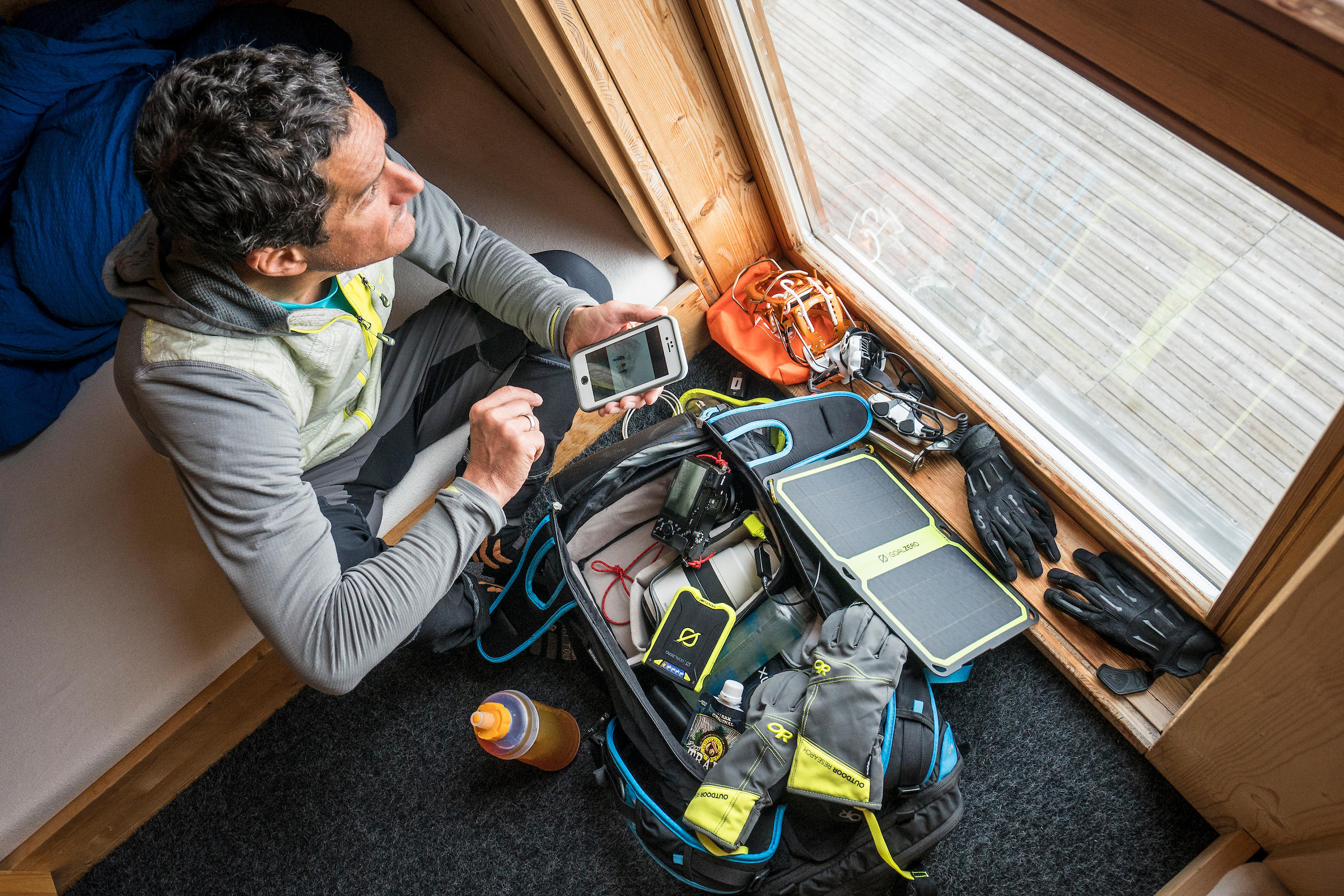 Photographer looks out window of hut, with all his gear in front of him