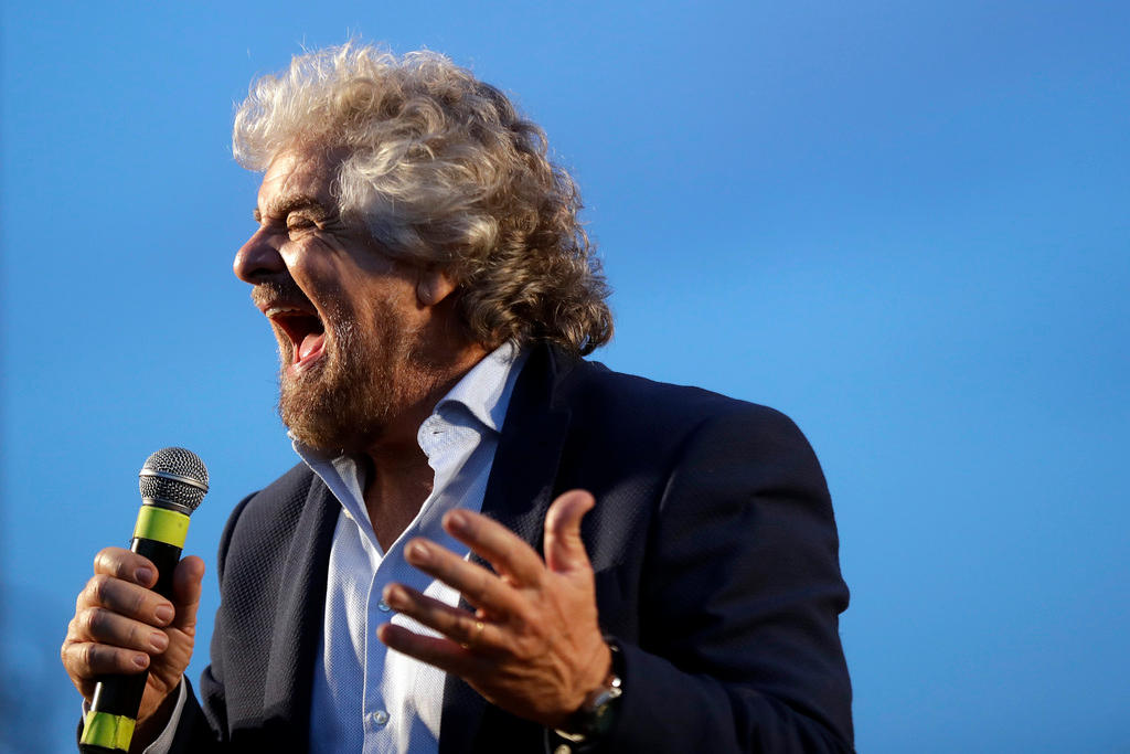Beppe Grillo urla durante un comizio (primo piano con fondo azzurro neutro)