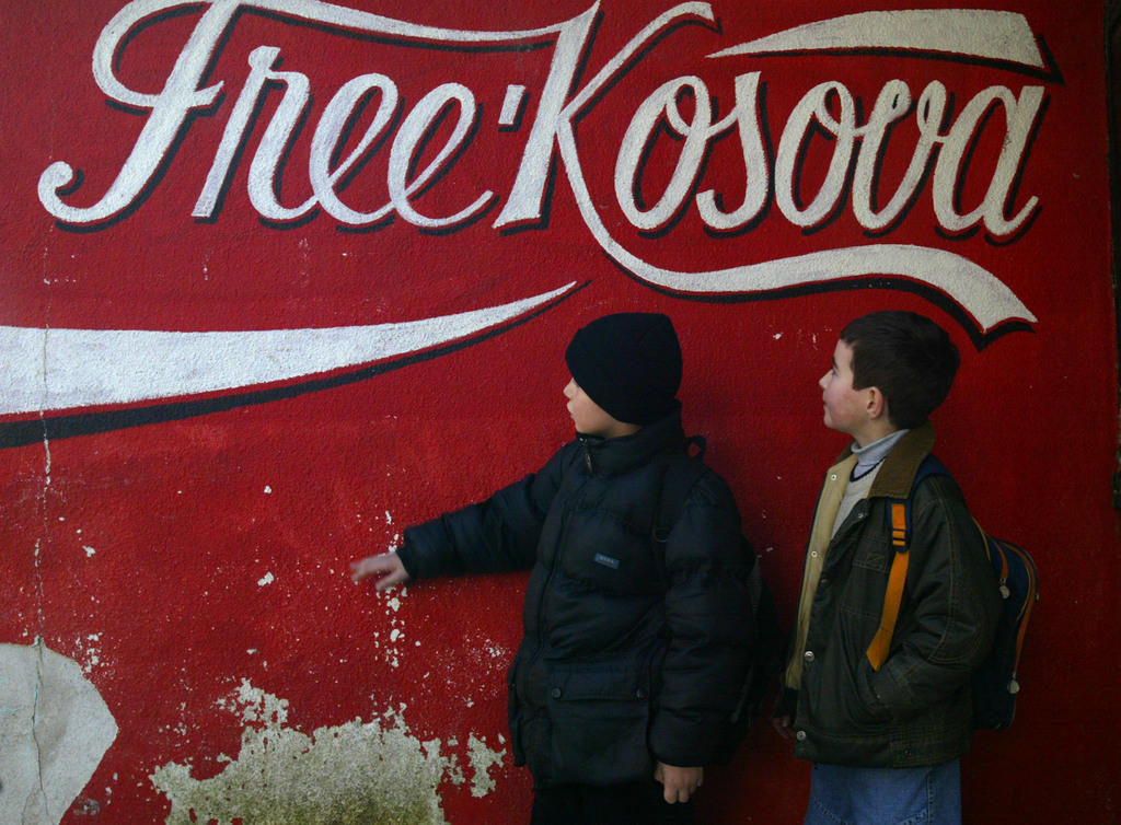 Kosovo Albanian children wait in front of graffiti reading Free Kosova in the ethnically divided Kosovo town of Mitrovica.