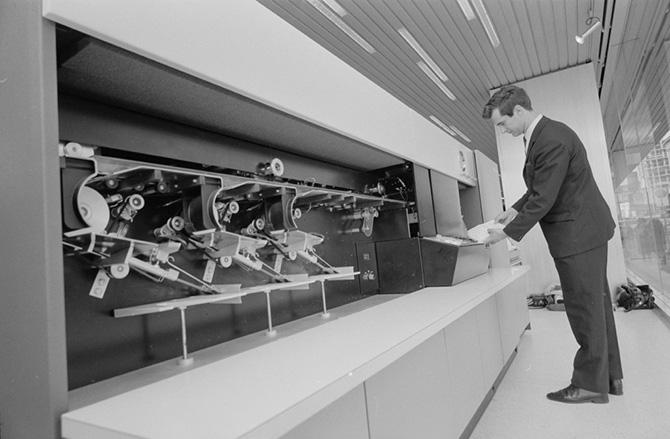 A man collects paper print-outs from a computer.