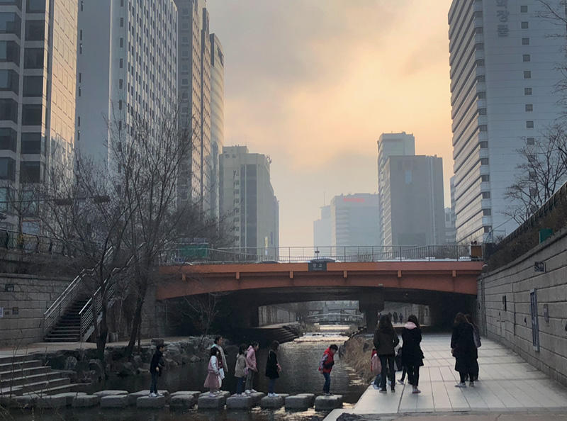 Downtown Seoul: People crossing a small river over stepping stones