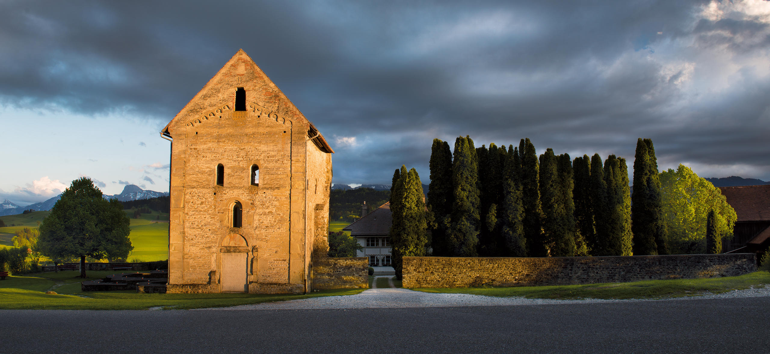 Un castello illuminato dal sole a fianco di un viale alberato.