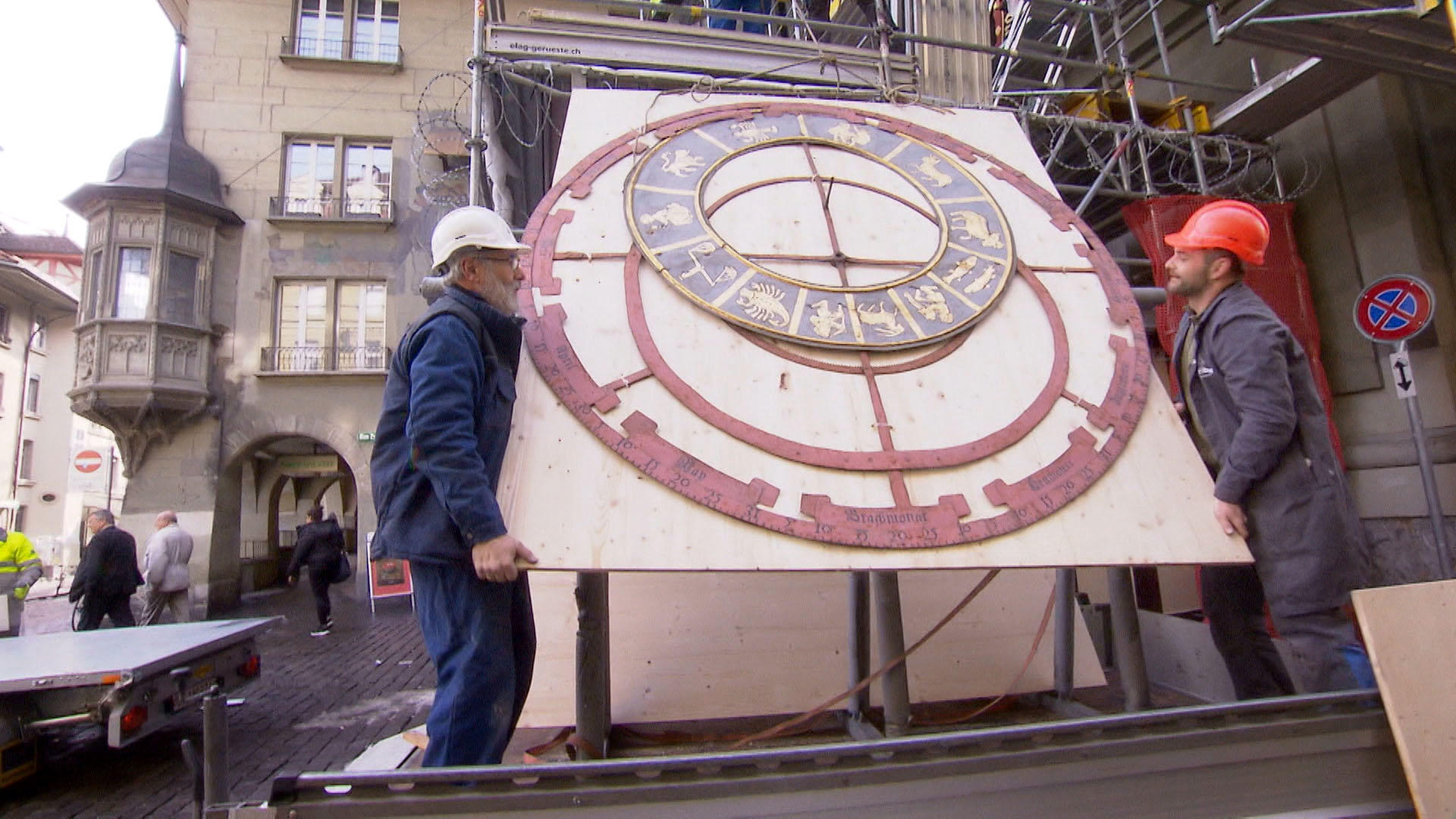 Two workers load part of the Zytglogge on the back of a truck.