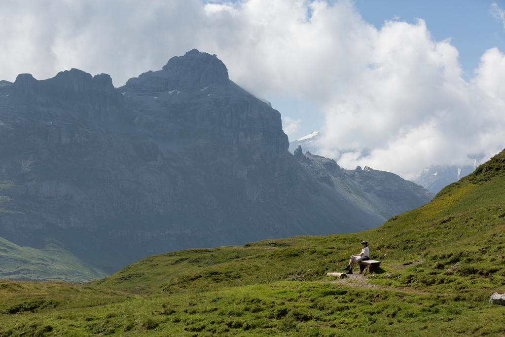 Femme sur un banc en face d une montagne.