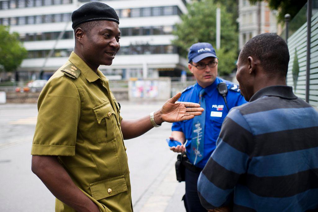 Ein schwarzer und ein weisser Polizist diskutieren mit einem schwarzen Mann auf der Strasse.