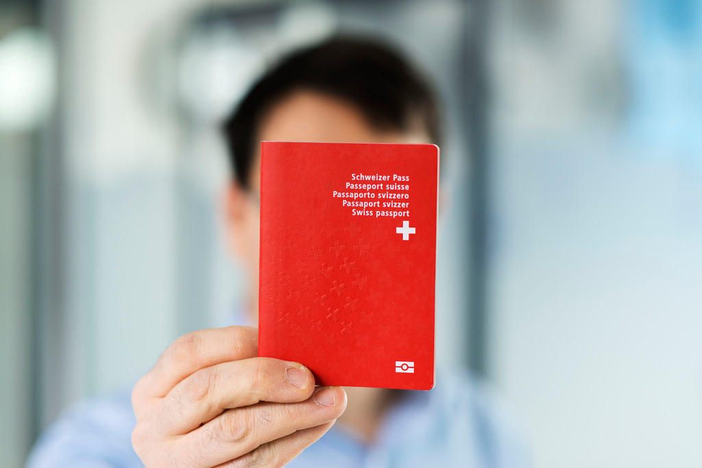رجل يحمل جواز سفر سويسري أحمر اللون أمام وجهه