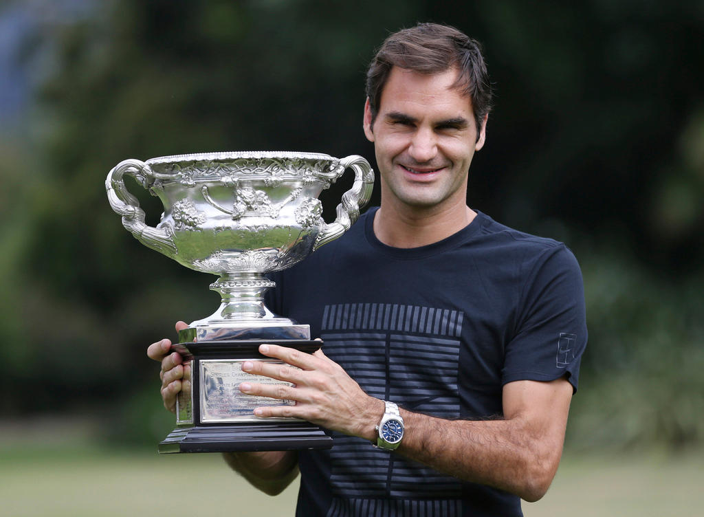 Federer holds up the Australian Open trophy wearing awatch