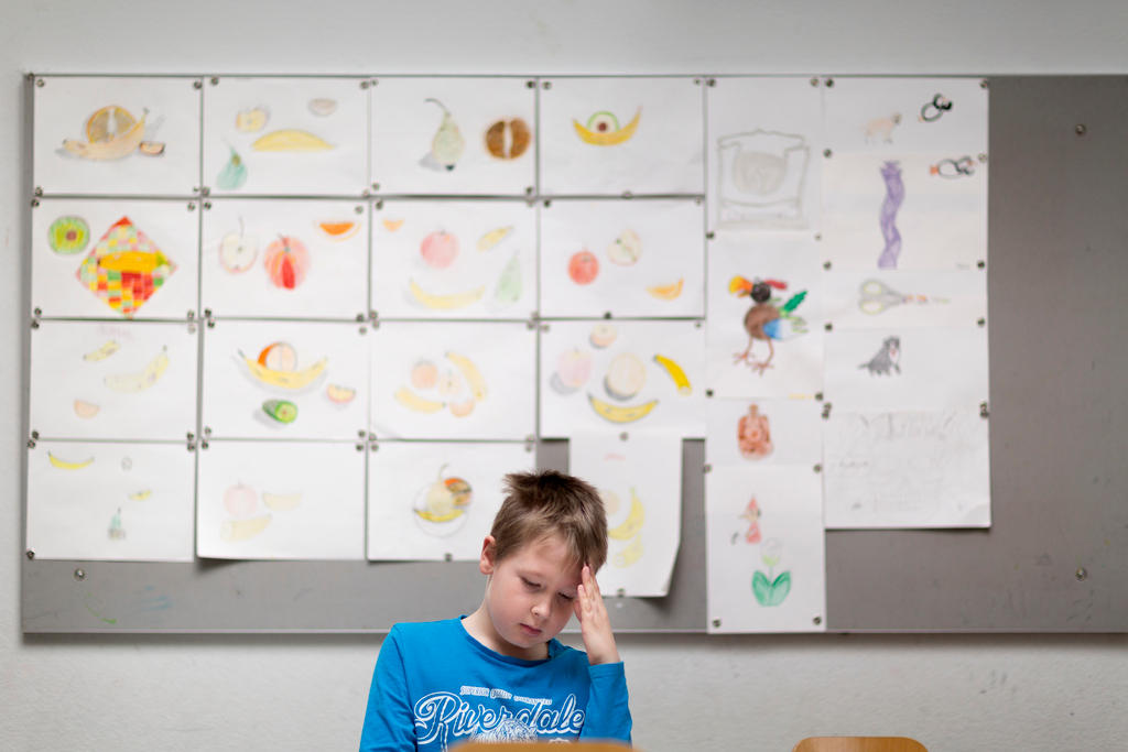 Boy in classroom with hand to head
