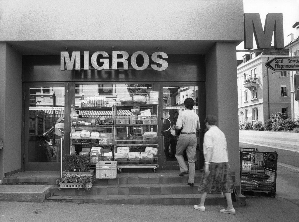 Homem e mulher entrando numa loja do Migros