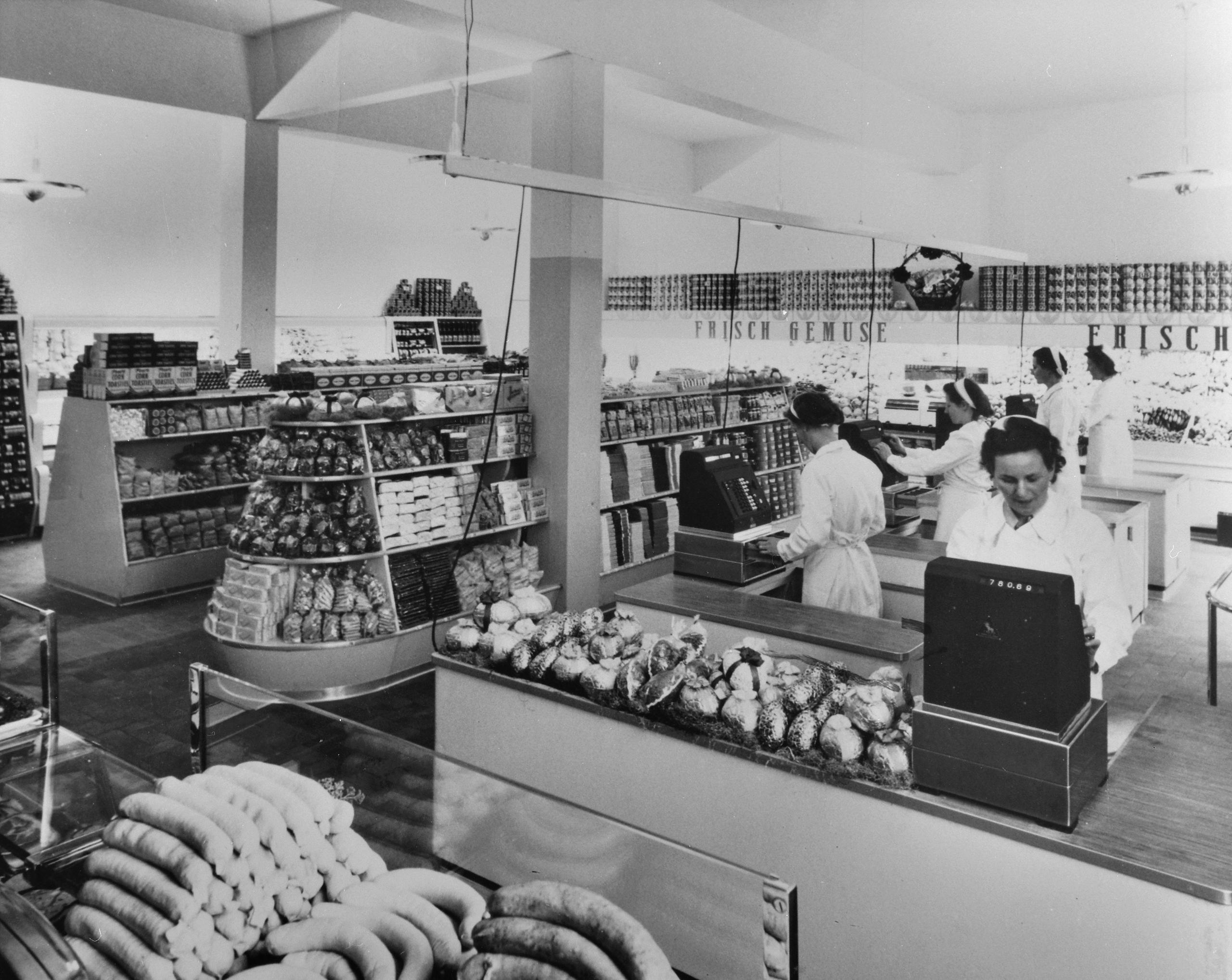 Interior do supermercado, com funcionárias preparando suas caixas registradoras