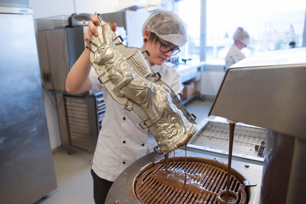 Une femme enlève l excès de chocolat du moule.