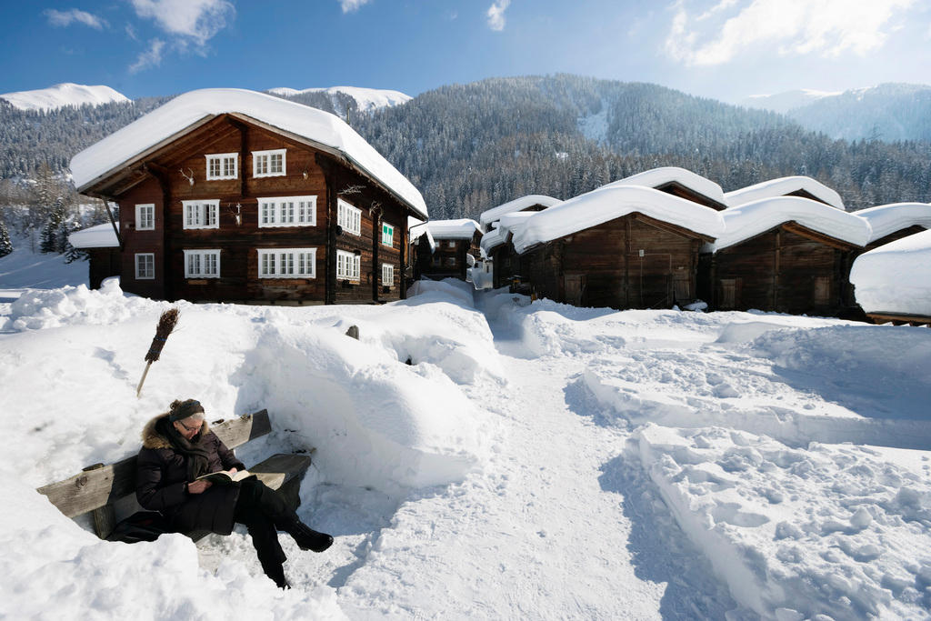 Mujer sentada en una banca rodeada de nieve