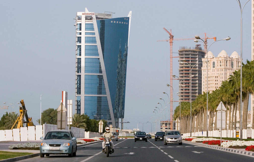strada di Doha con sullo sfondo il grattacielo in vetro della catena alberghiera Moevenpick