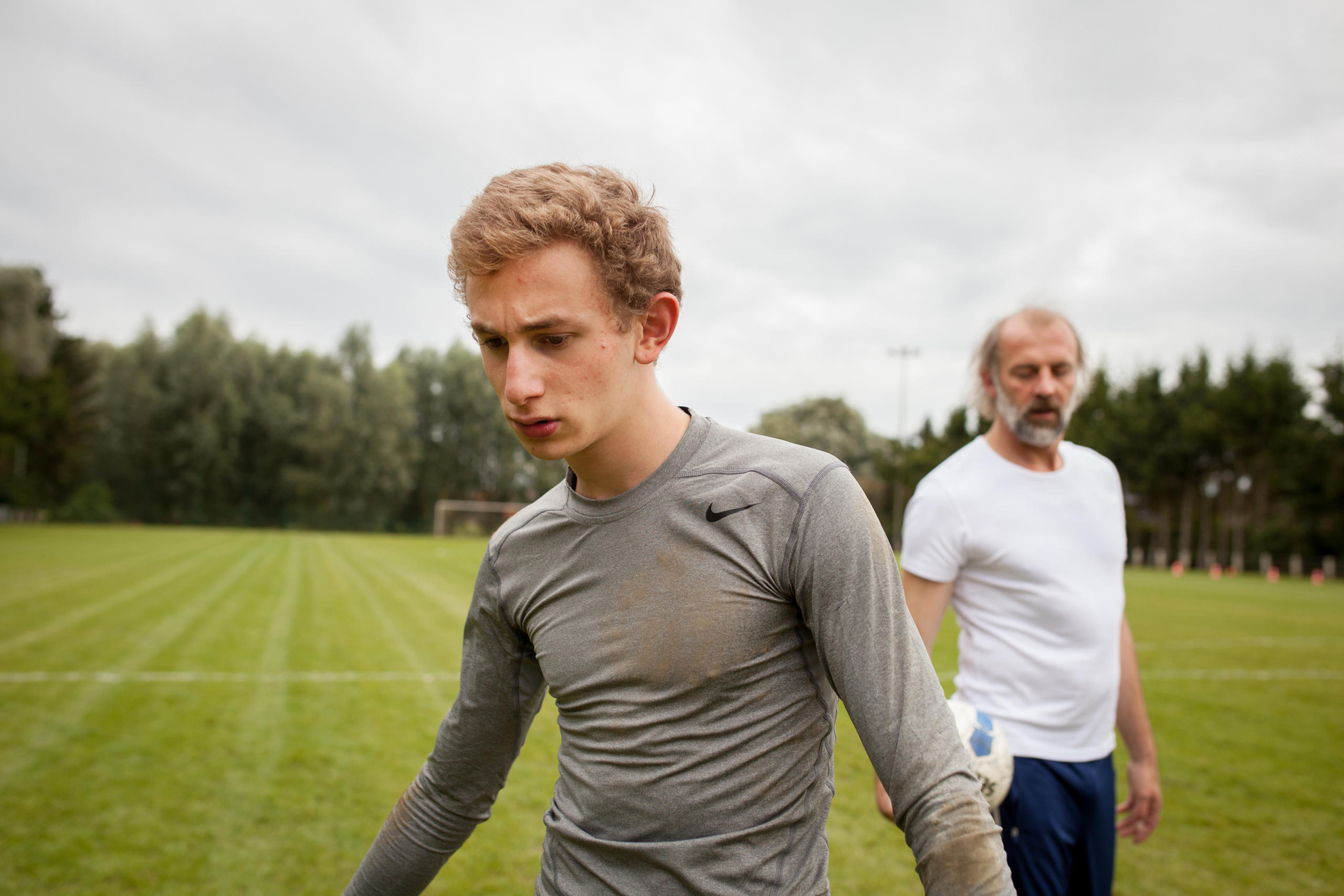 Young man in foreground behind him stands a an older man