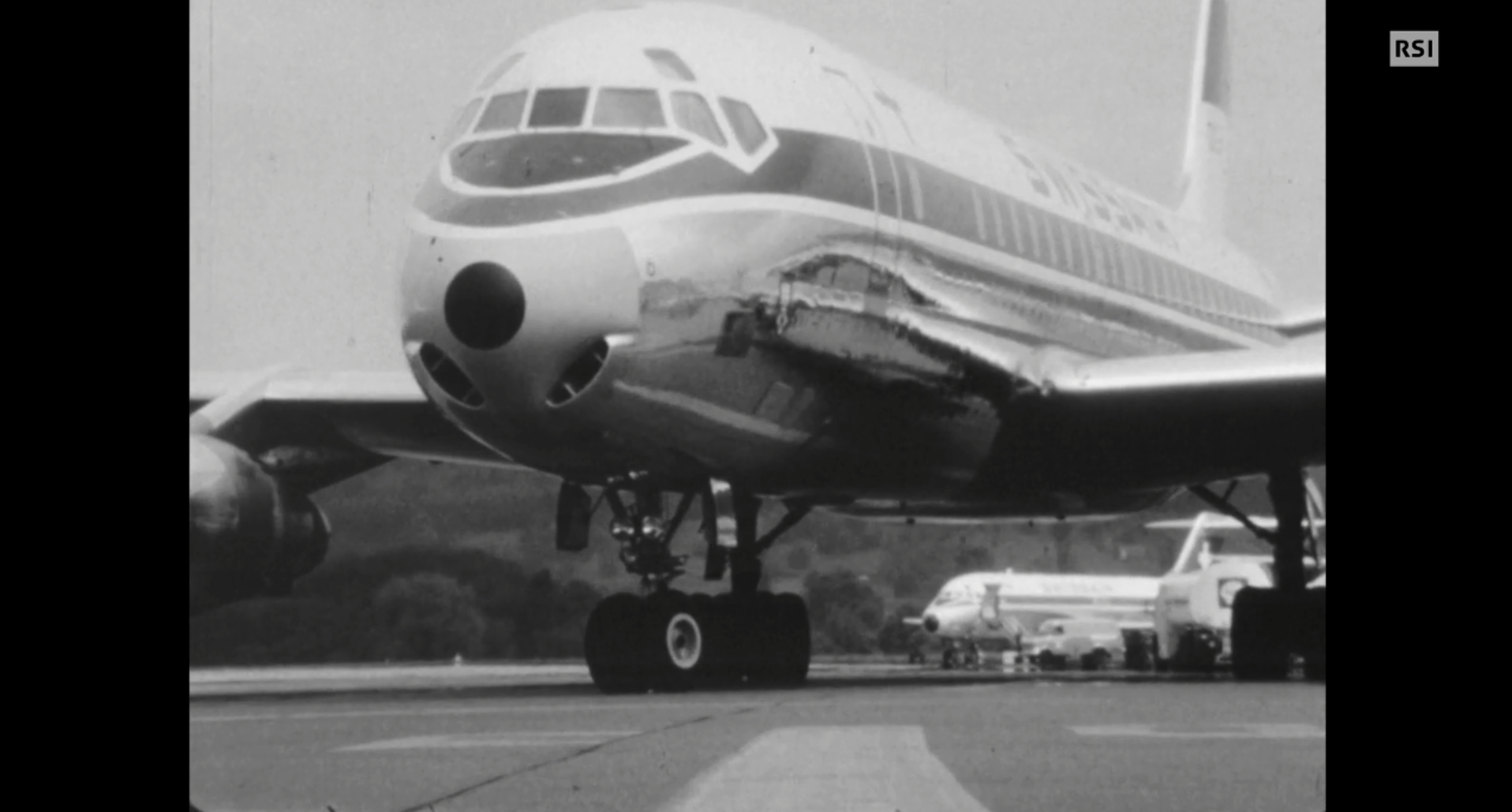 Immagine di un aereo Swissair che rulla prima del decollo; in lontananza altri velivoli e mezzi