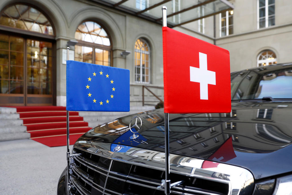 Swiss and EU flags flying on a black car