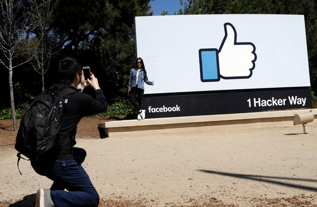 ragazzo fotografa un cartellone con il pollice di facebook