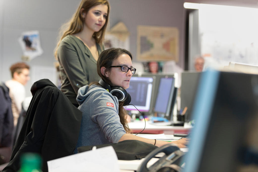 Two young journalists in front of computer screens