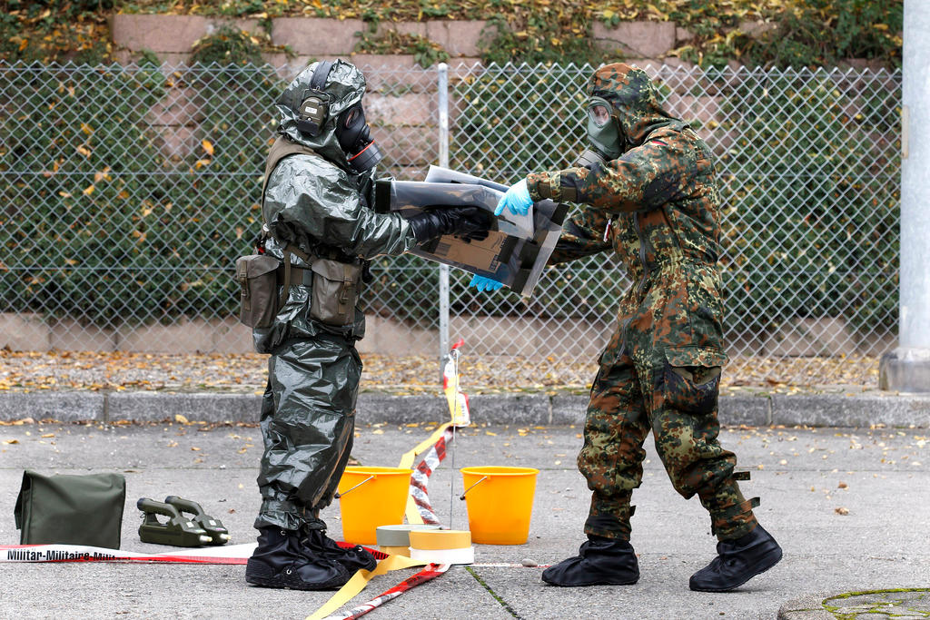 Two soldiers in gas masks and protective clothing handover x-rays