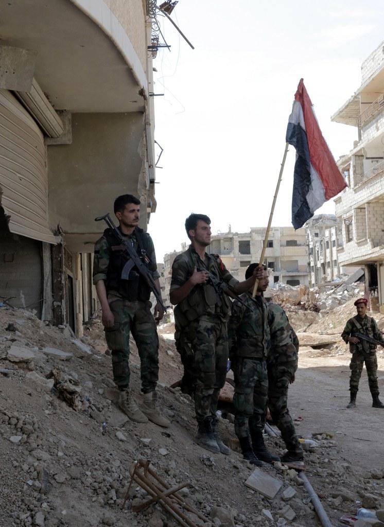 soldati sventolano una bandiera siriana