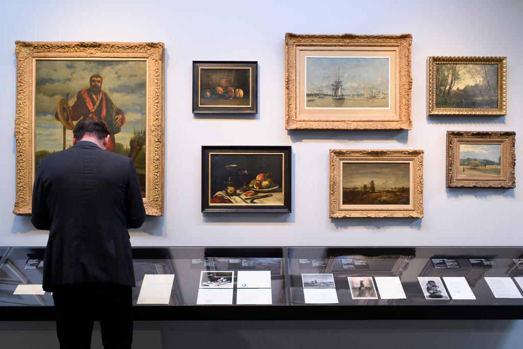 A person looks at the paintings with his back to the camera.