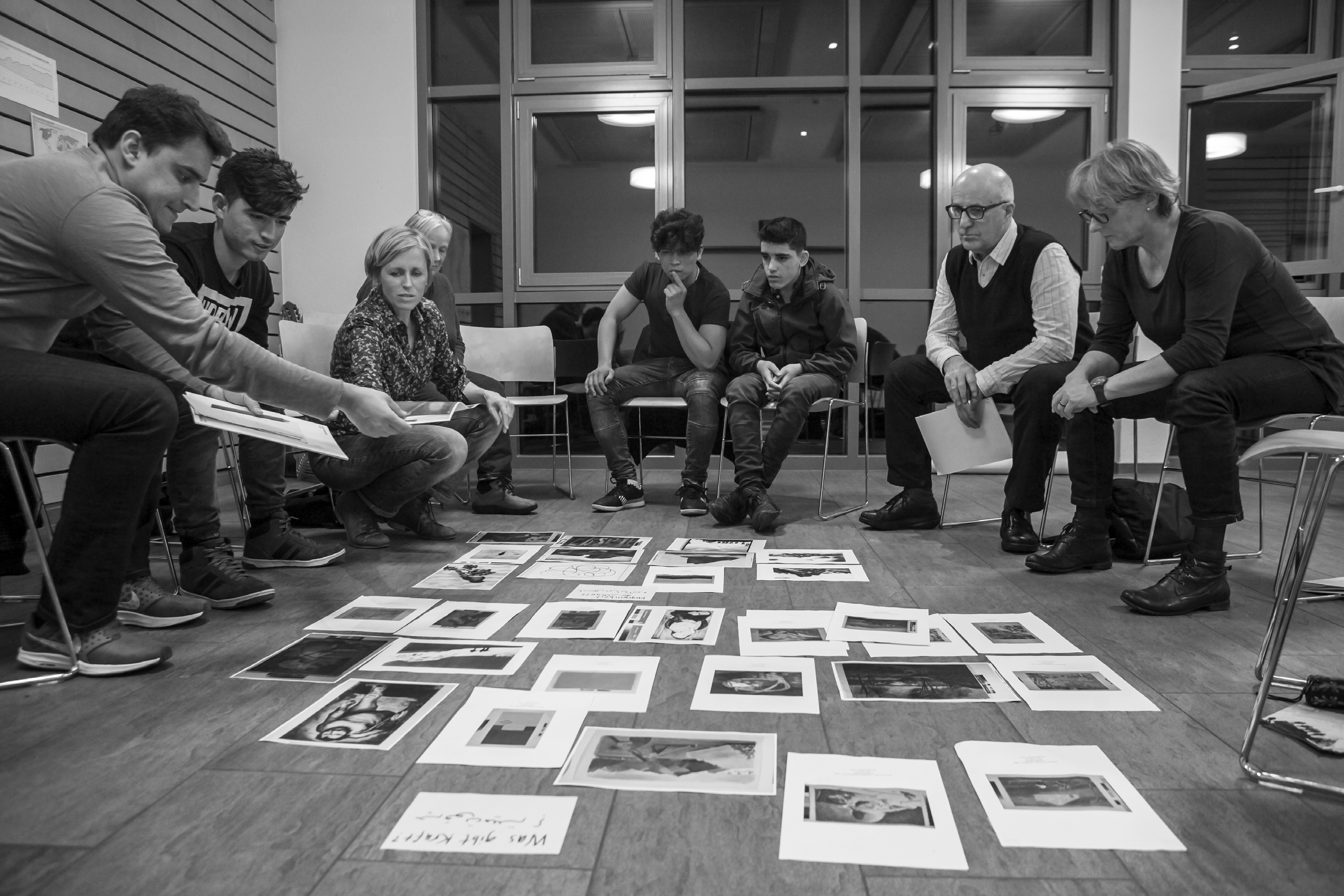 Group of men and women sitting in a circle, with pictures at their feet