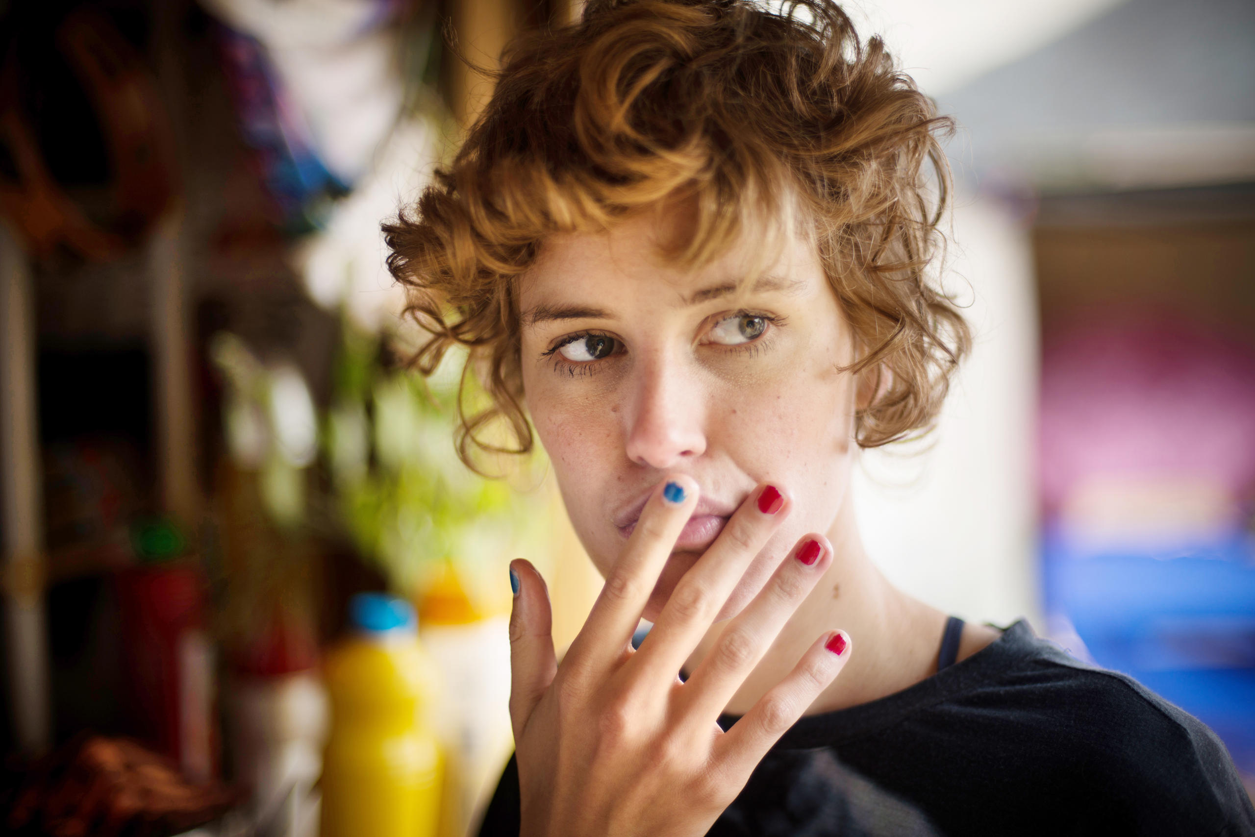 A young woman touches the lips of her mouth with her fingers.