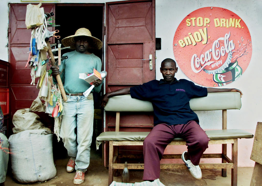A picture of a street vendor sitting in front of a shop with an English sign