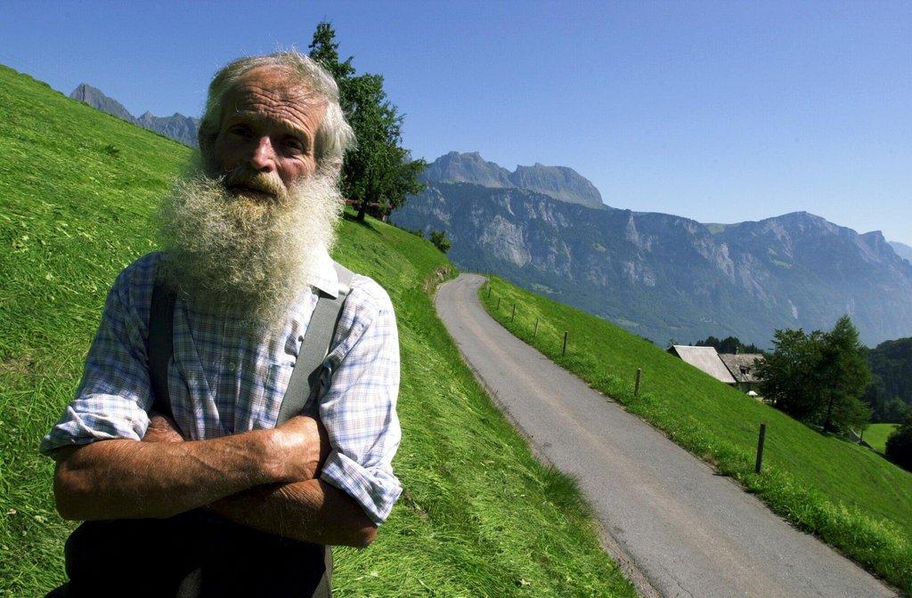 Ein Bergbauer steht vor einer Strasse