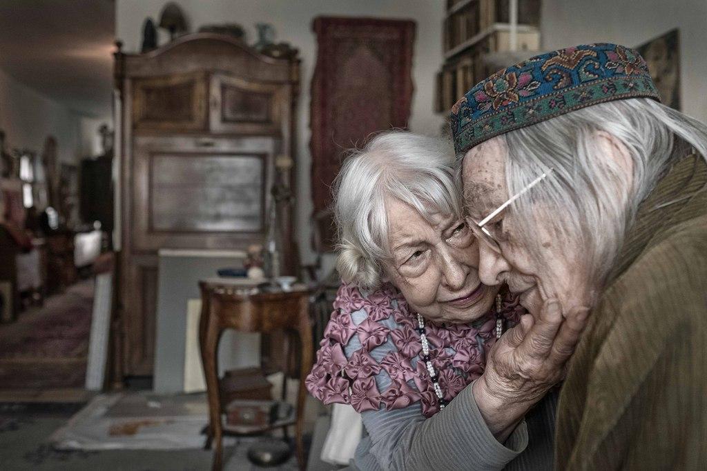 una donna molto anziana accarezza il viso di suo marito