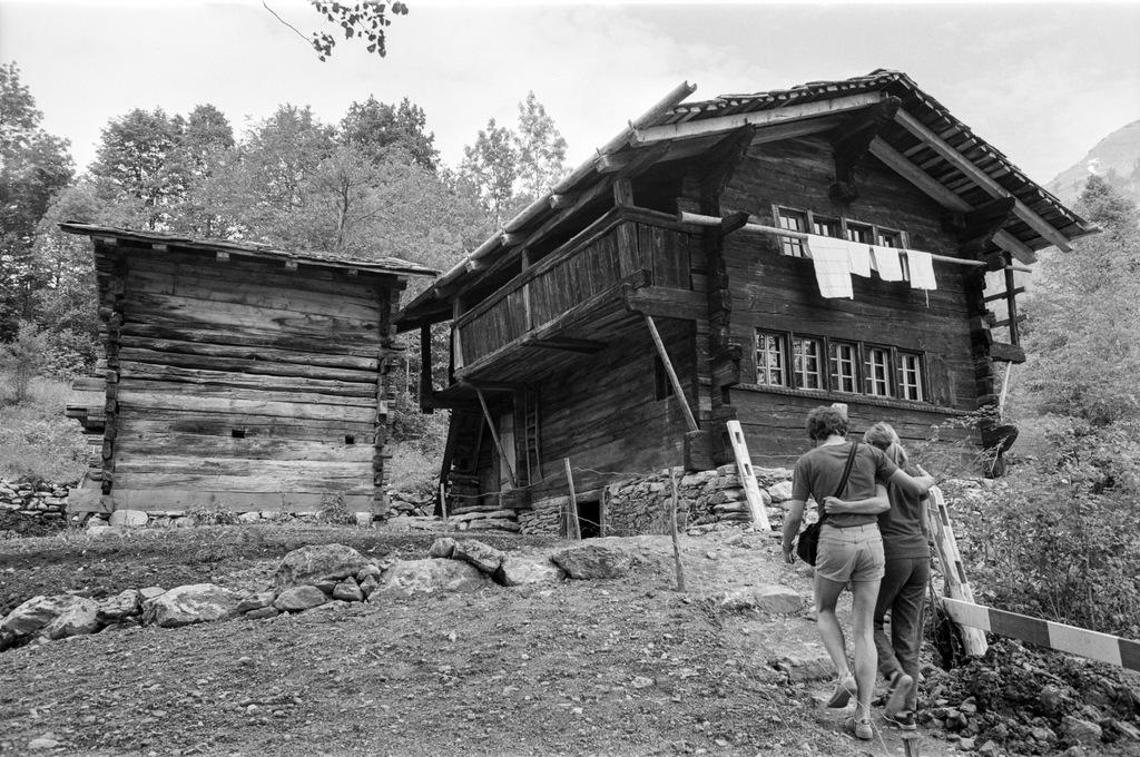 una coppia passeggia davanti a una casa di legno e un fienile.