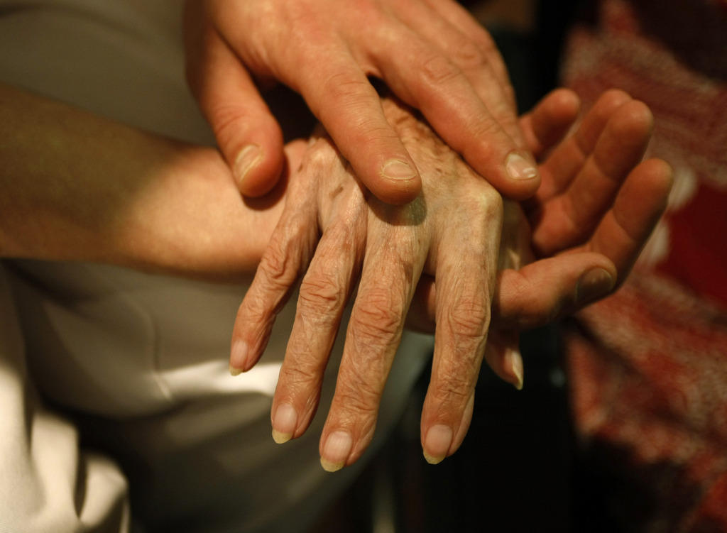 Las manos de una persona joven sostienen la mano de una persona mayor.