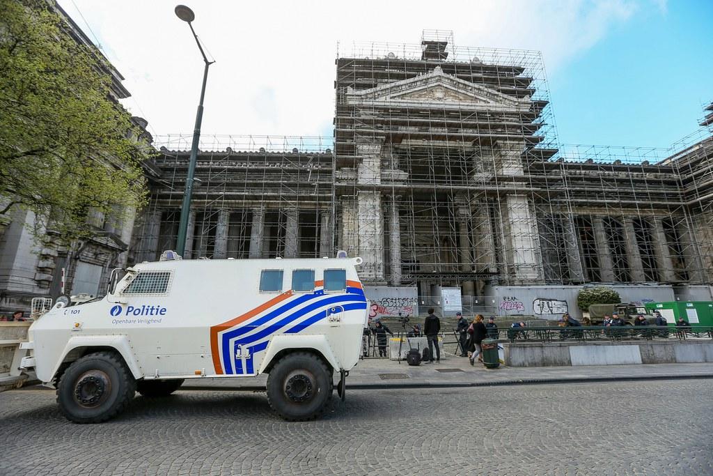 Palazzo di giustizia coperto da impalcature. In primo piano, un mezzo corazzato della polizia