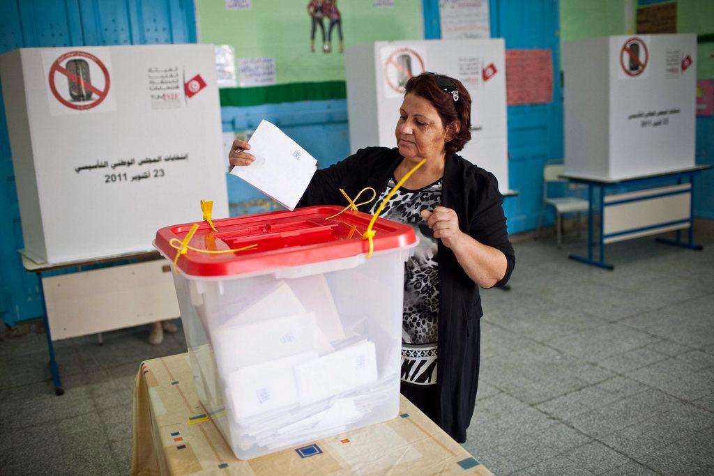 Una mujer deposita su voto en una urna.