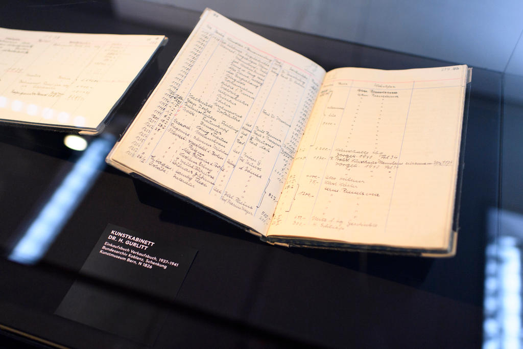 Picture of an open handwritten book beneath a glass case