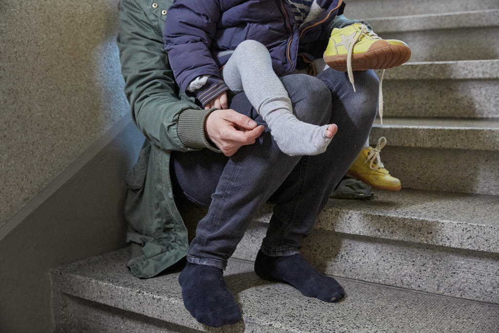 A picture of a woman sitting with their children on a staircase without shoes on