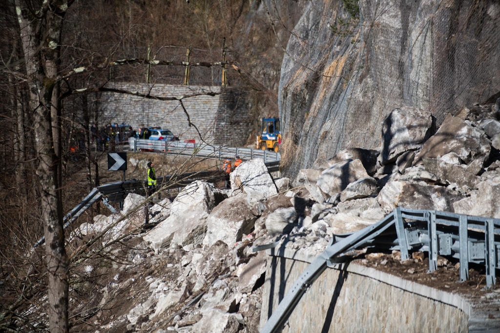 Immagine della strada ricoperta da massi, in lontananza veicoli della polizia e dei soccorsi italiani