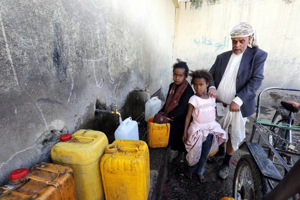 يمنيون يملؤون صفائحهم بمياه صالحة للشرب من صهريج مياه مُتبرع بها في العاصمة صنعاء